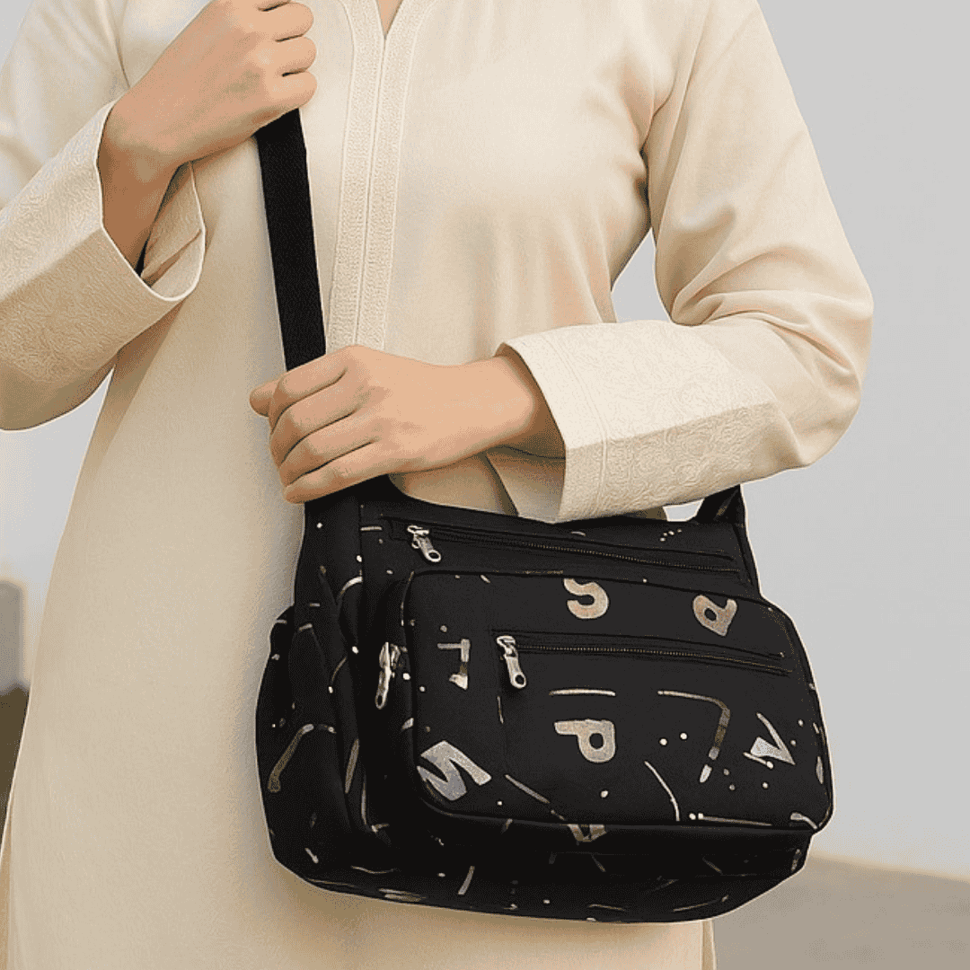 Person holding a black crossbody bag with letter patterns