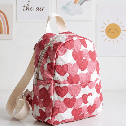 Multicolor small Backpack perfect for travel with pink heart pattern on a white surface