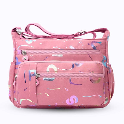 Large stylish crossbody alphabet bag in lavender with multicolor letter print, featuring multiple zippered compartments for fashion and versatility.
