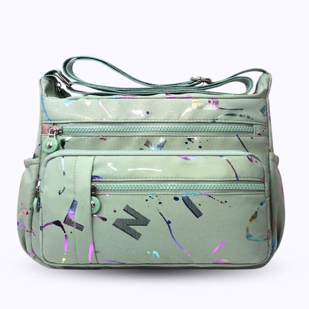 Large stylish crossbody alphabet bag in sage green with multicolor paint splatter and bold letter prints, ideal for fashion-forward versatility.