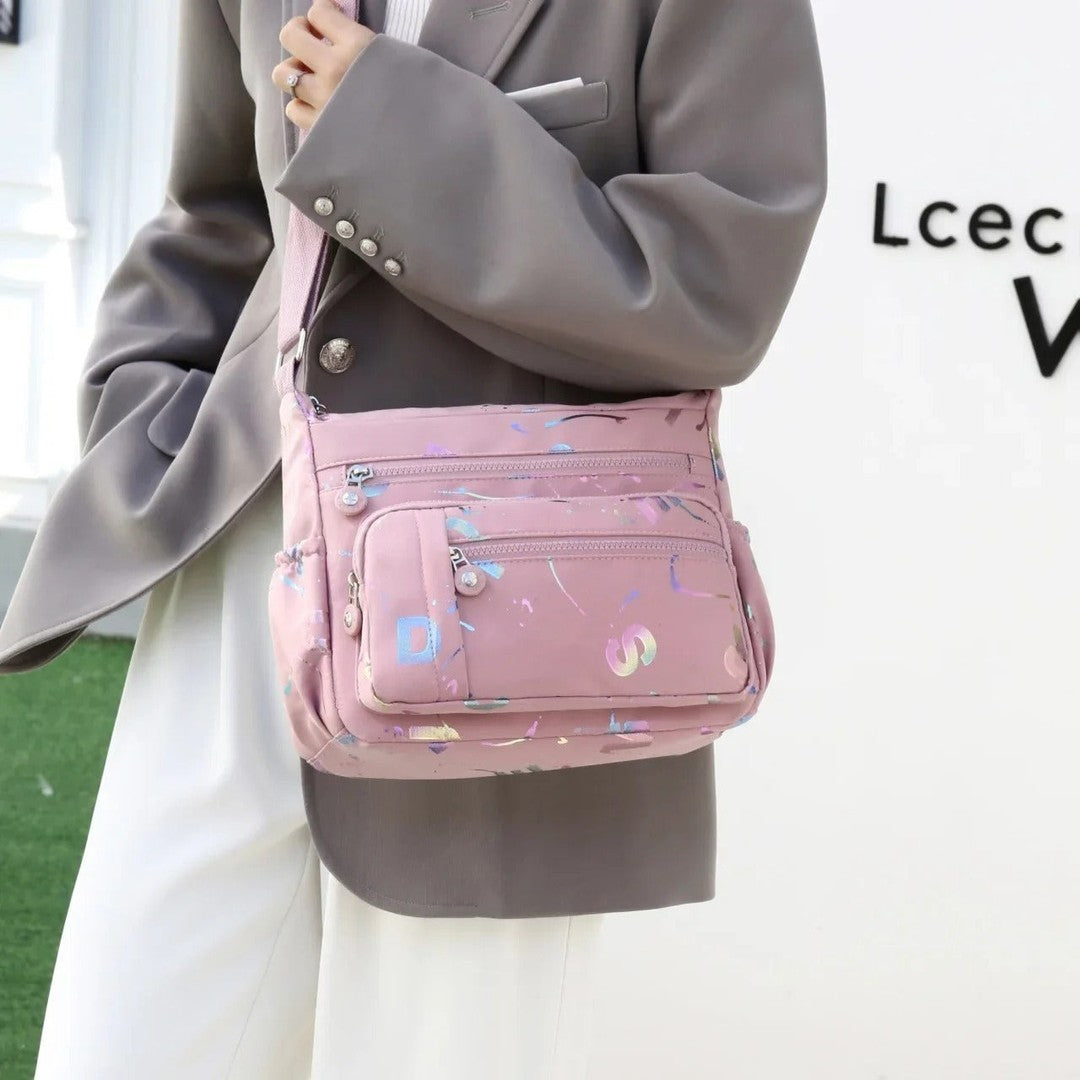 Large stylish crossbody alphabet bag in lavender with multicolor letter print, featuring multiple zippered compartments for fashion and versatility